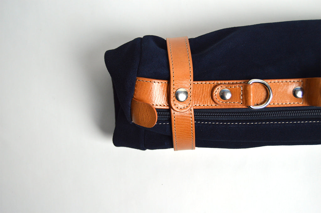 Bolso de viaje plegable elaborada en serraje azul marino con detalles en piel de alta calidad. 